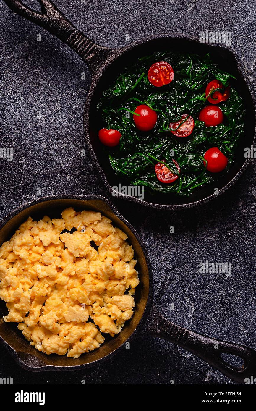 Omelette cuite et épinards avec tomates dans des casseroles, vue de dessus. Banque D'Images