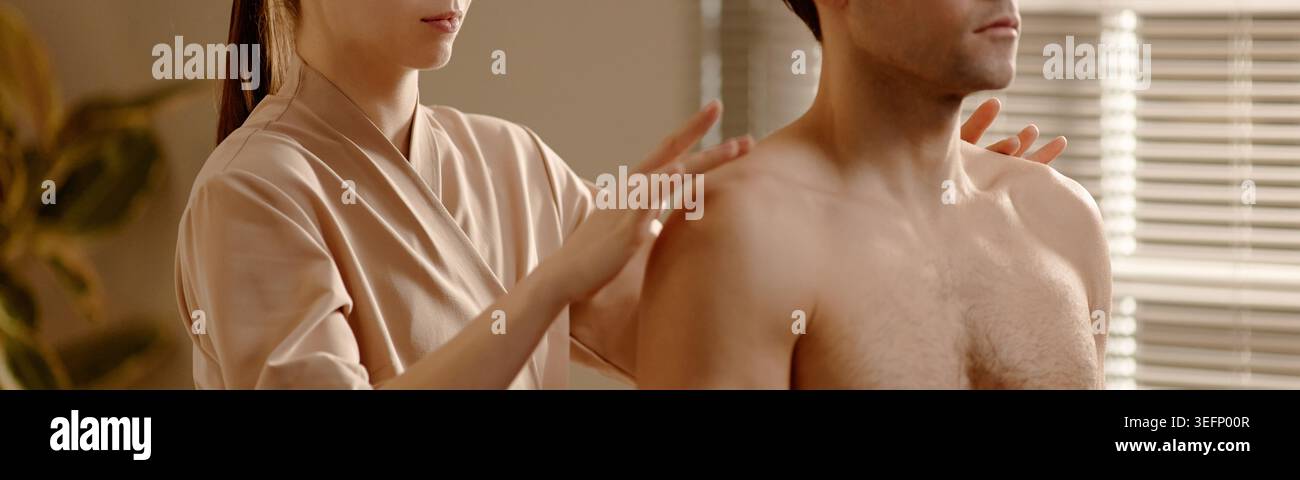Femme adulte massant homme adulte pendant la séance de thérapie de bien-être Banque D'Images