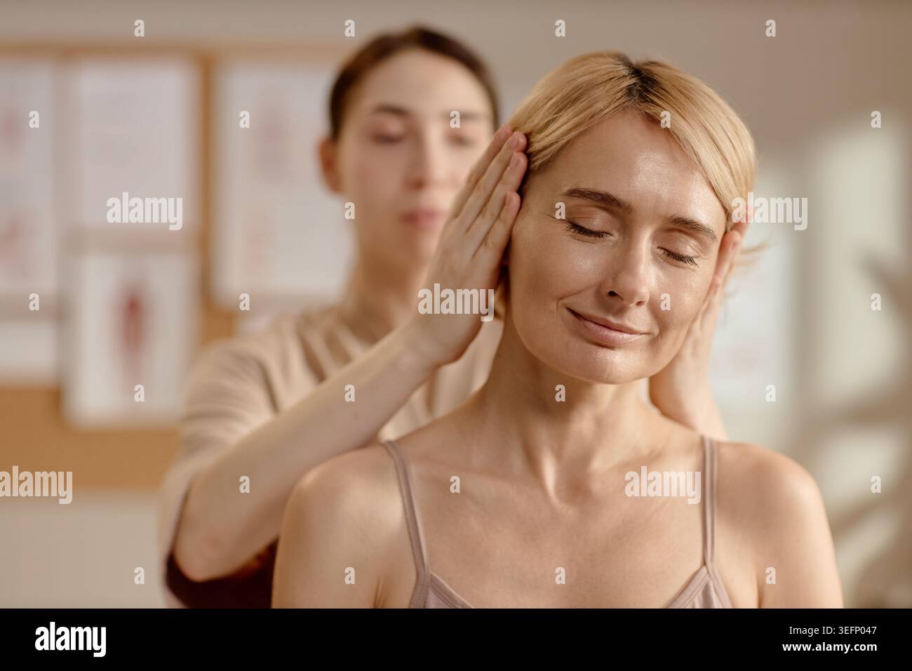Femme d'âge moyen recevant un massage de la tête pour thérapie de bien-être Banque D'Images