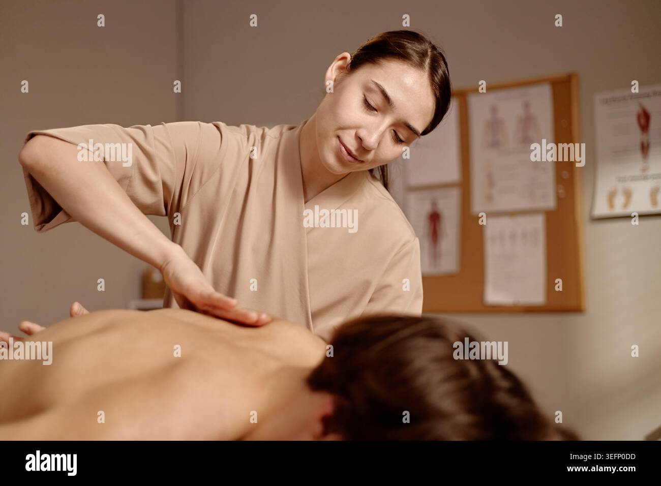 Thérapeute femme adulte appliquant une pression manuelle pour la récupération du dos Banque D'Images
