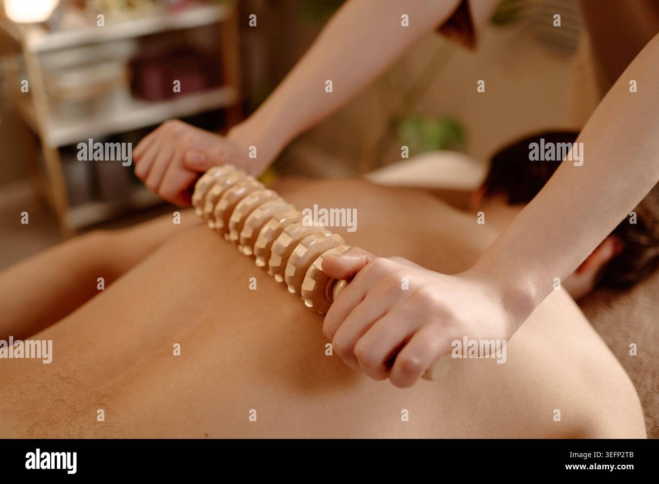 Homme adulte recevant un massage à rouleaux en bois pour la thérapie de bien-être Banque D'Images