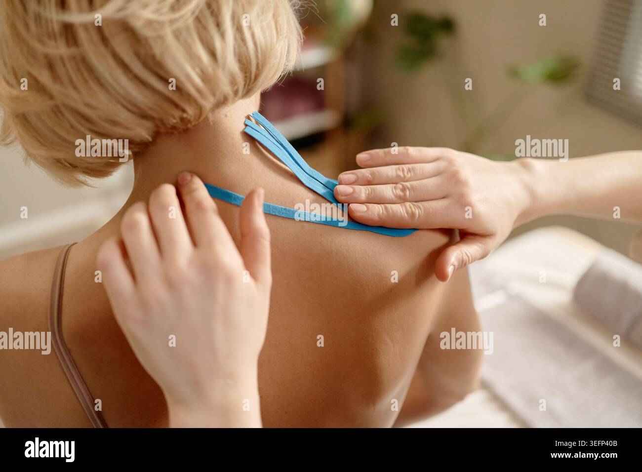 Femme adulte recevant Kinesiology Taping pour le soulagement de la douleur du cou Banque D'Images