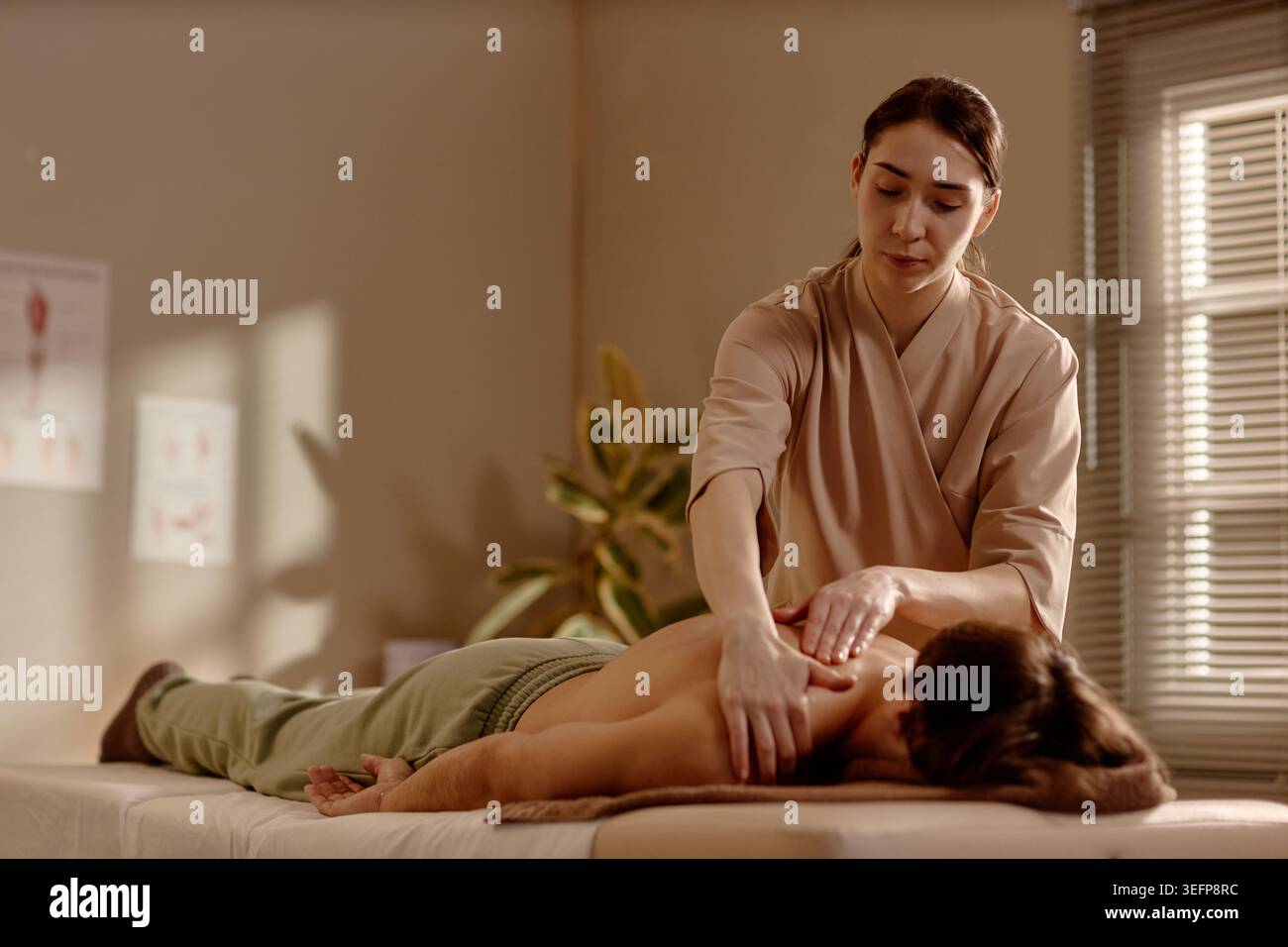 Femme adulte massothérapeute traitant l'homme dans la clinique de bien-être Banque D'Images