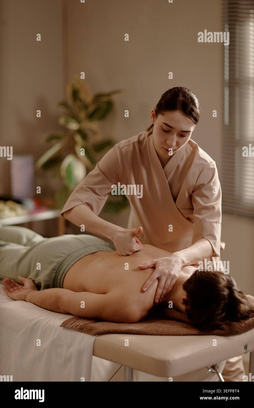 Thérapeute de femme adulte effectuant un massage de récupération musculaire sur l'homme Banque D'Images
