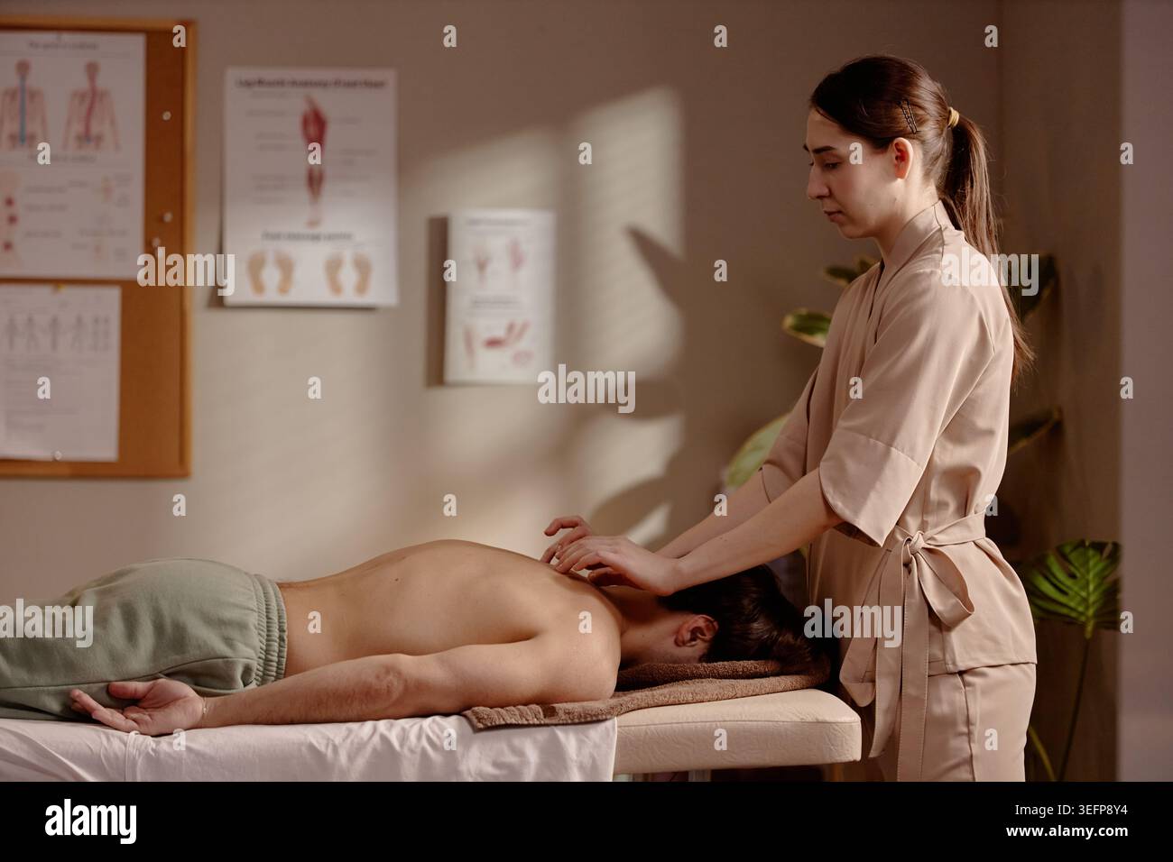 Femme adulte massothérapeute traitant l'homme dans la clinique de bien-être Banque D'Images