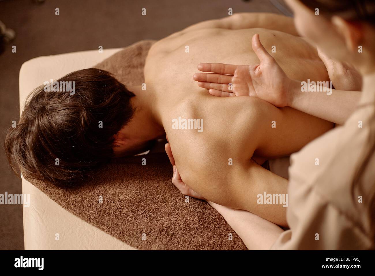 Homme adulte recevant un massage du dos pendant un soin au spa de bien-être Banque D'Images