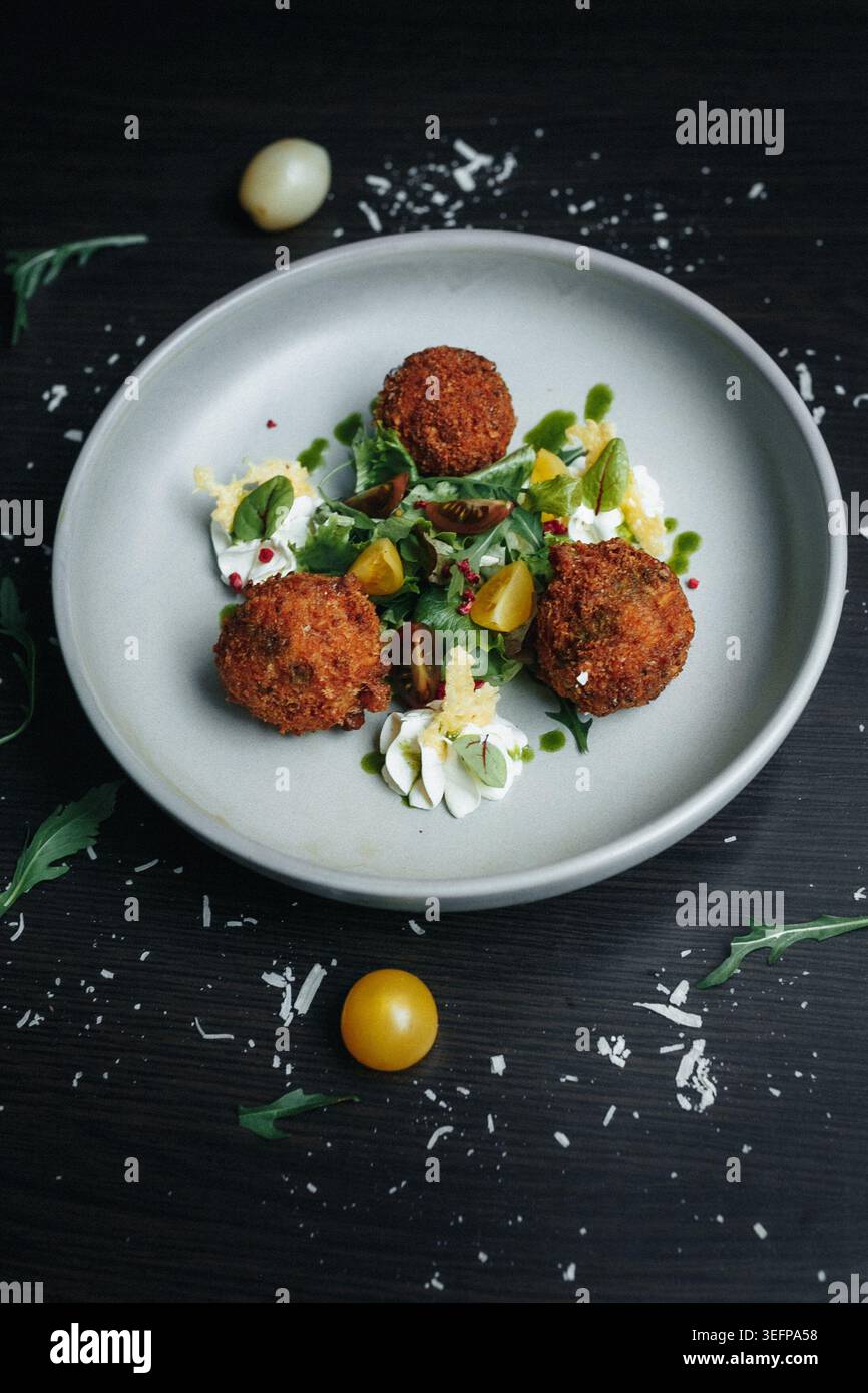 Croquettes avec sauce aux herbes et tomates cerises sur table sombre Banque D'Images