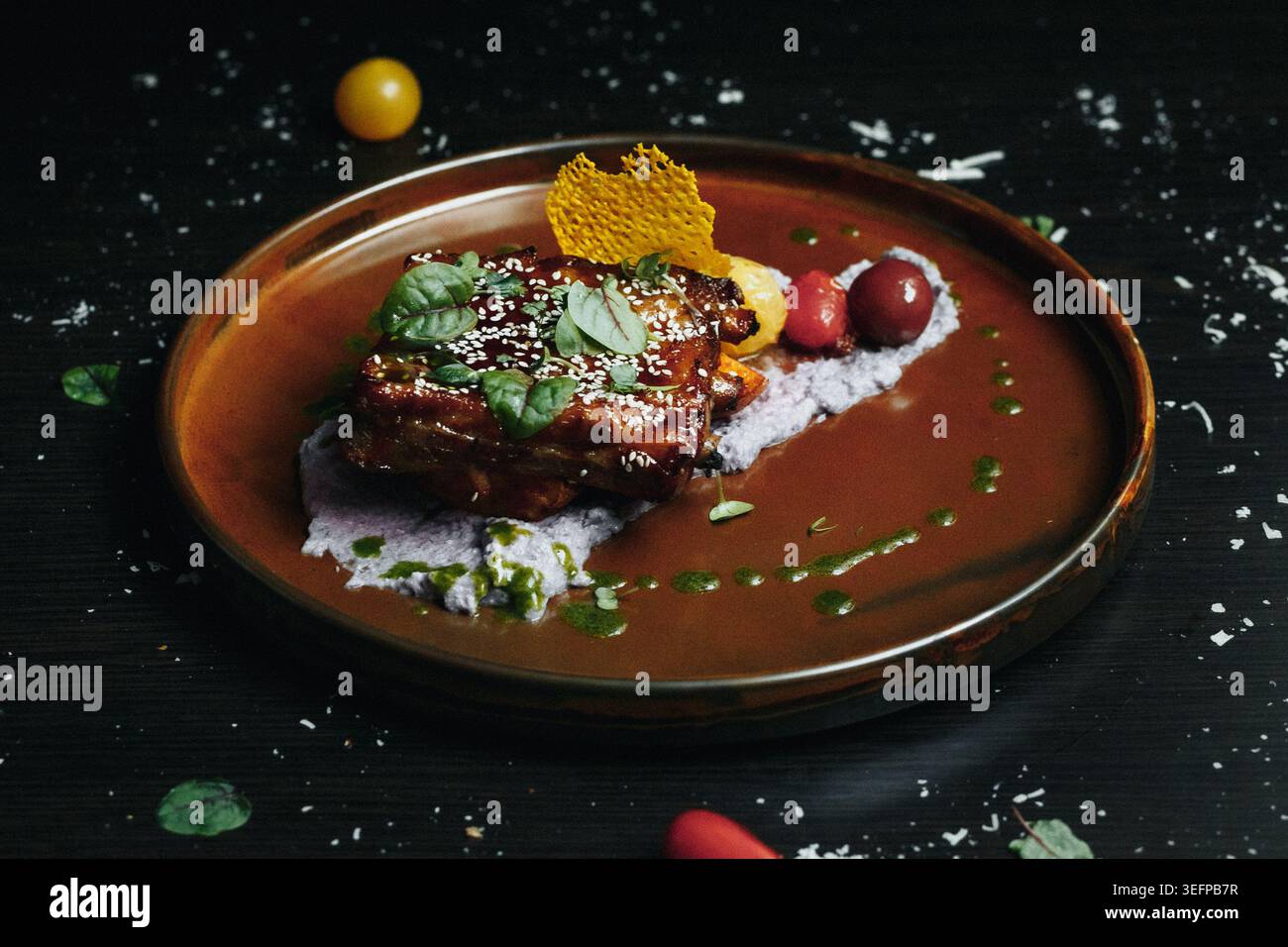 Plat gastronomique servi sur une assiette brune rustique avec des garnitures vibrantes et de la sauce Banque D'Images