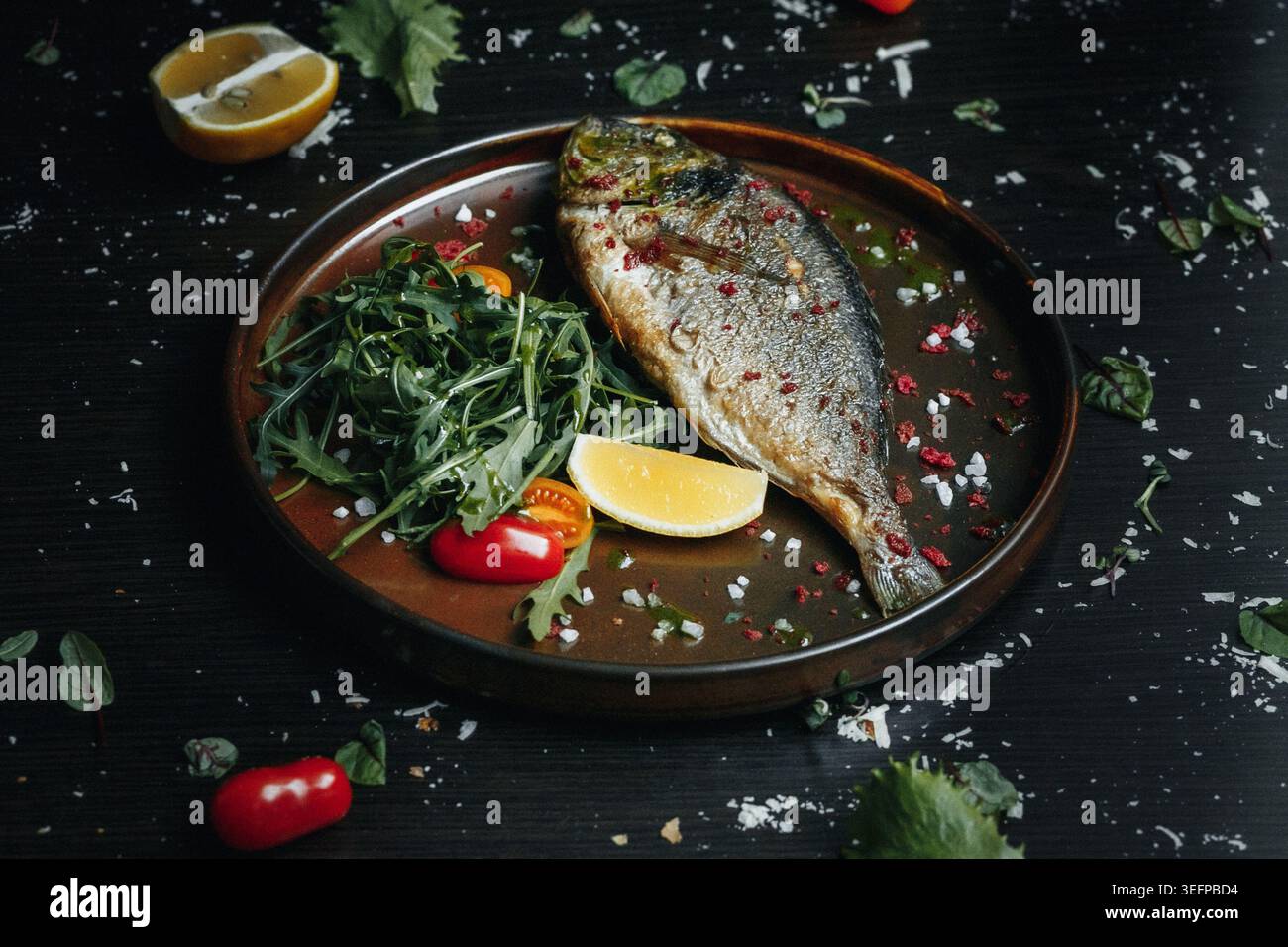 Filet de poisson grésillé avec des légumes verts, des agrumes et des épices sur un plateau en bois Banque D'Images