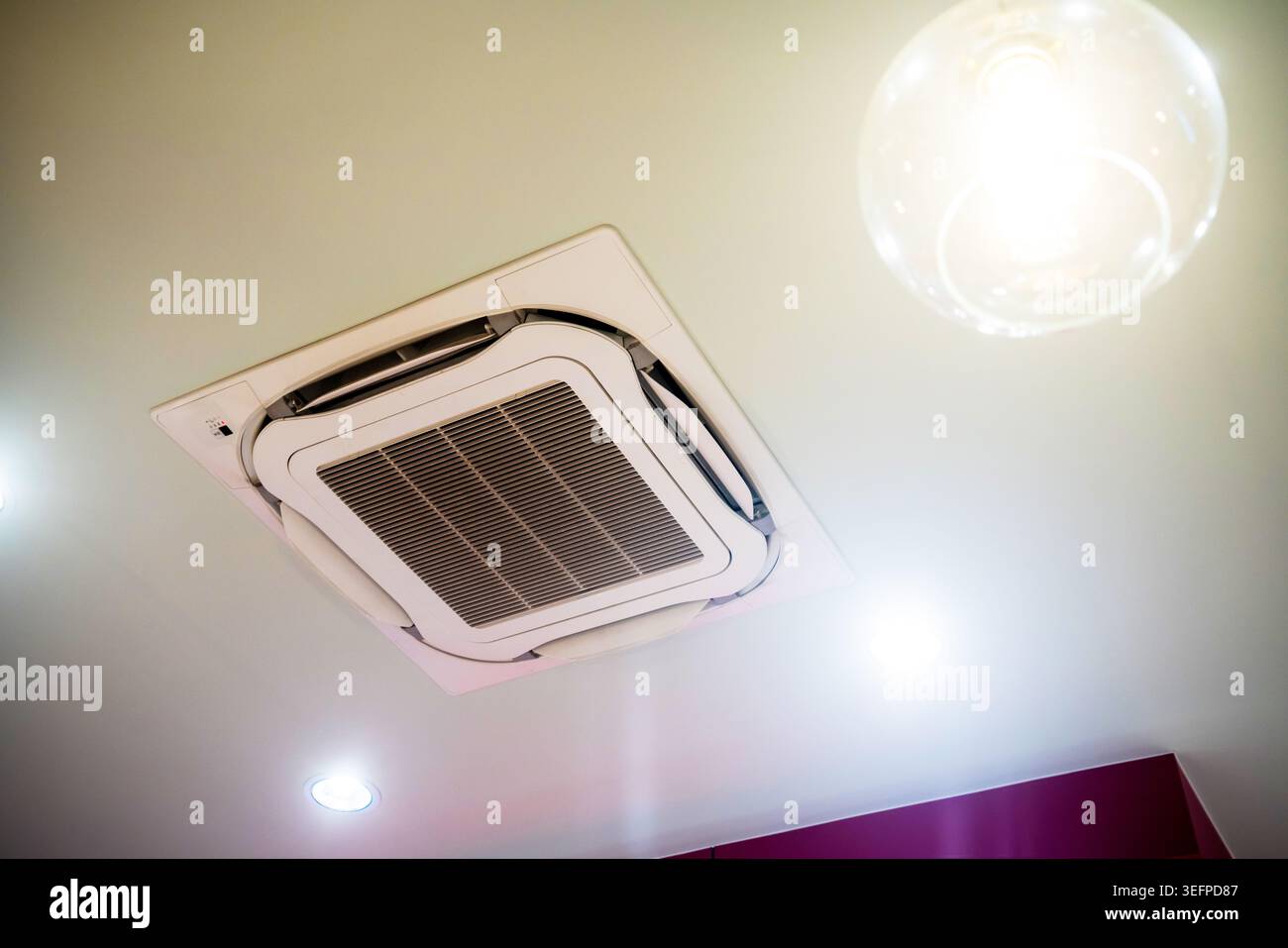 Cette image montre une unité de climatisation moderne montée au plafond avec éclairage intégré, avec un design élégant et une grille de ventilation, commune in con Banque D'Images