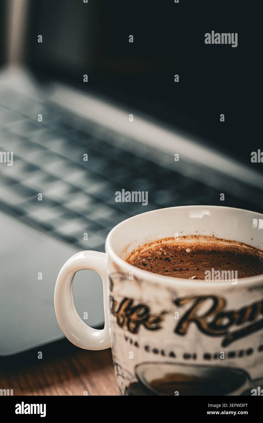 Café traditionnel dans une tasse en céramique souvenir avec texte à thème italien sur un bureau en bois. Banque D'Images