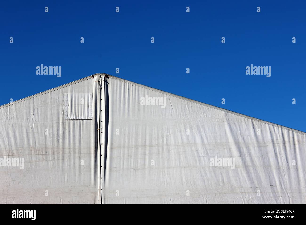 Ligne de toit triangulaire d'une tente de chapiteau commerciale blanche contre un ciel bleu clair et profond Banque D'Images