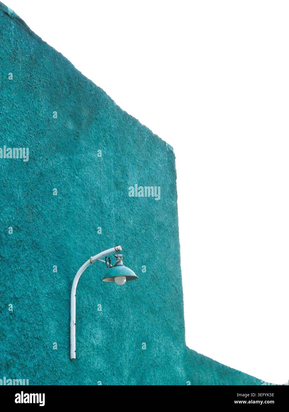 La toile de fond murale texturée sarcelle prend en charge un lampadaire blanc à bras incurvés, créant une scène urbaine minimaliste avec une géométrie audacieuse, des lignes épurées et une tranquillité Banque D'Images