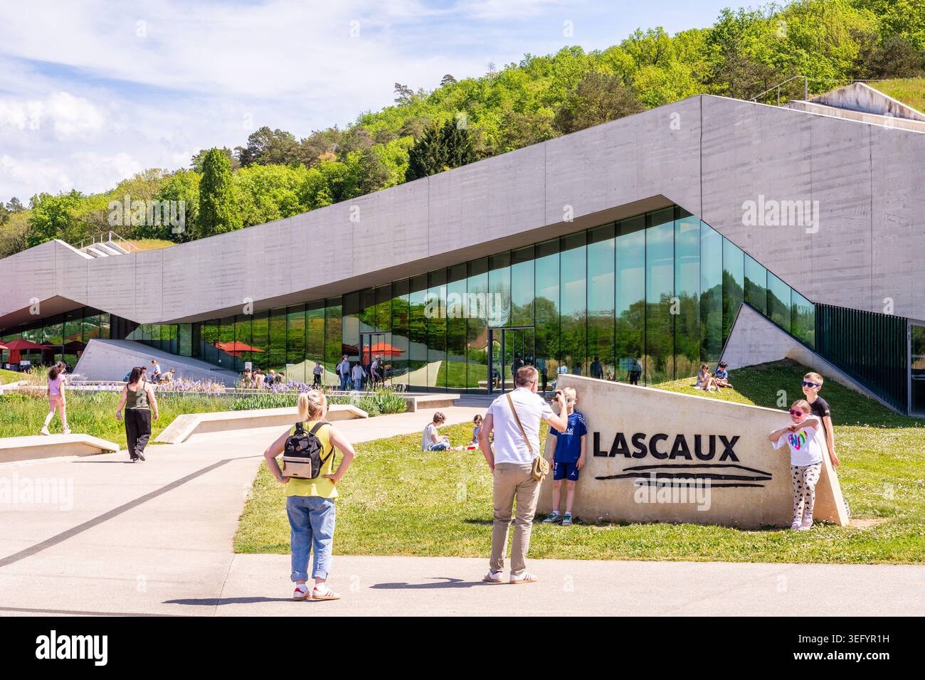 Un homme de famille prend en photo ses enfants devant le panneau du Centre International d’Art pariétal, maison de Lascaux IV à Montignac, France. Banque D'Images