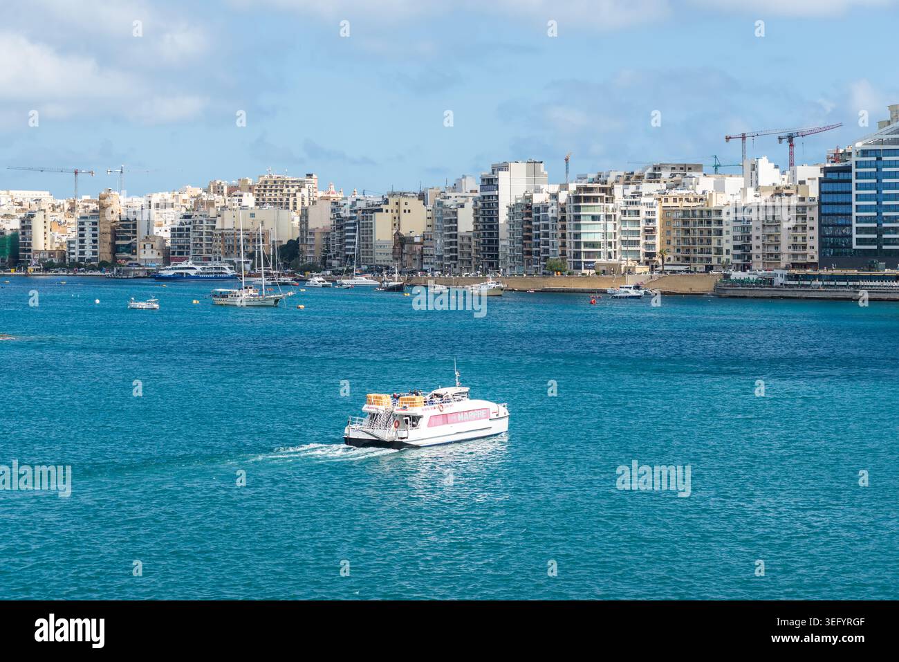 Sliema, Malte - 16 mai 2025 : ferry de passagers voyageant de Sliema à la Valette à travers les eaux turquoises du port de Marsamxett avec Waterfro moderne Banque D'Images