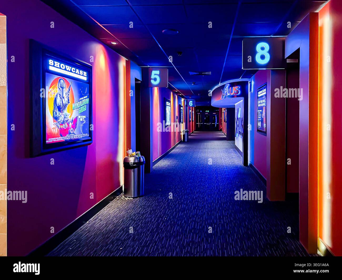 Vue le long d'un couloir d'un cinéma multiplex menant aux écrans, sombre mais éclairé par un éclairage bleu d'ambiance et d'humeur Banque D'Images