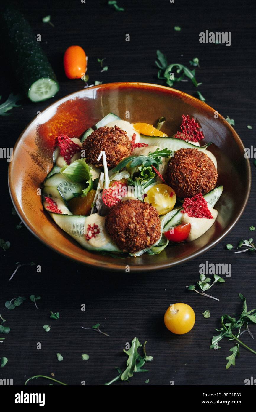 Bol à salade falafel avec légumes frais et herbes sur fond de bois foncé Banque D'Images