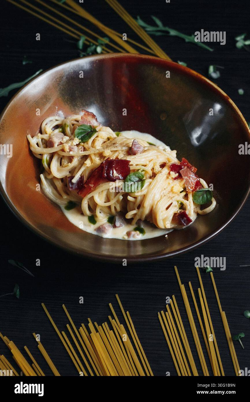 Délicieux plat de pâtes dans un bol en bois, garni de légumes verts et de tomates rouges Banque D'Images