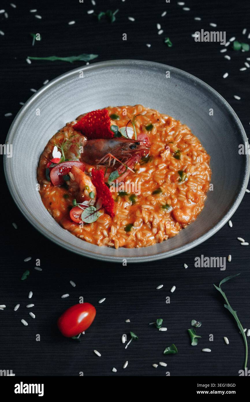 Risotto aux fruits de mer riche garni de tomates fraîches et de basilic Banque D'Images