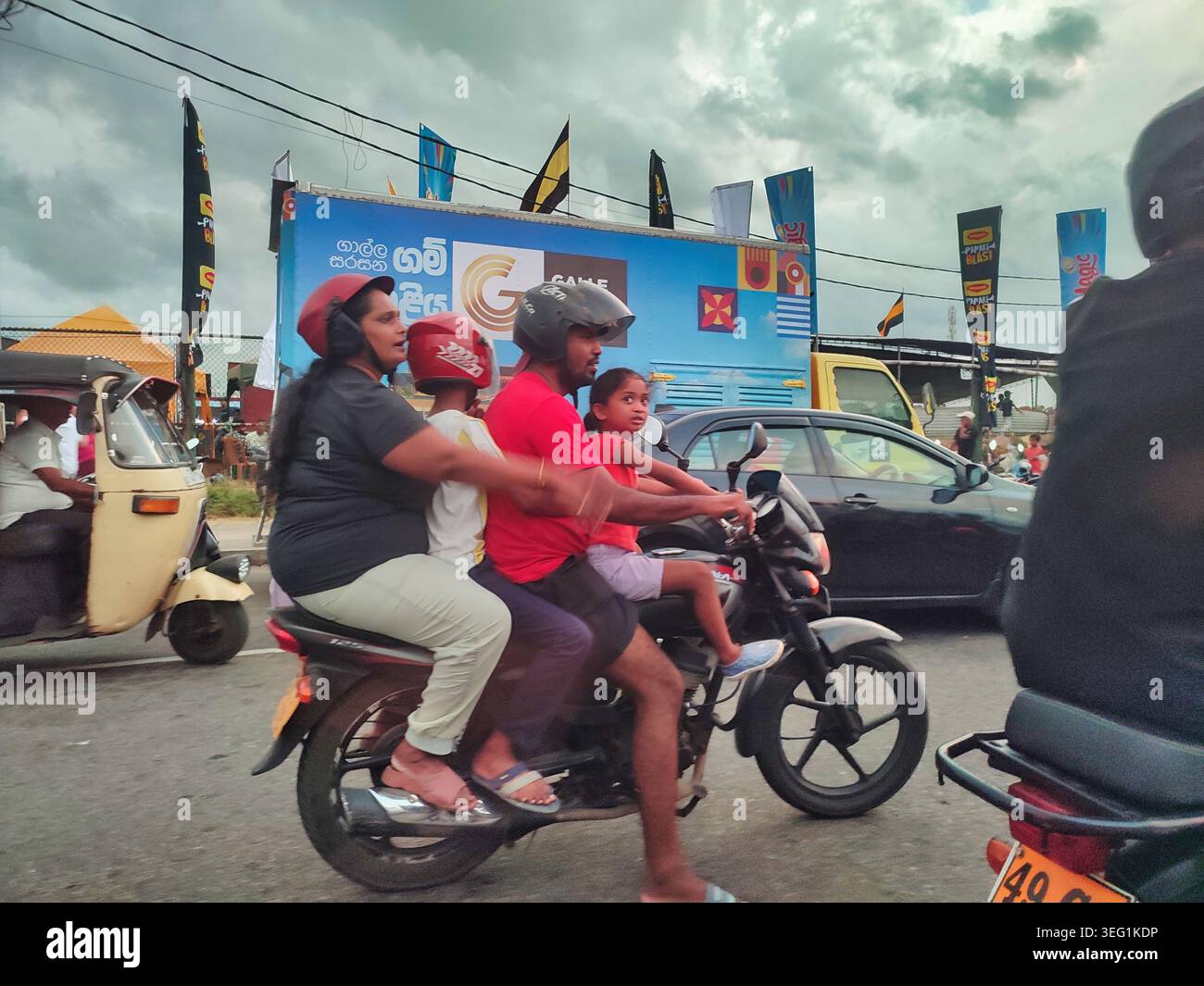 Une famille de deux parents et deux enfants conduisant une moto dans un trafic dense devant le stade international de cricket Galle au Sri Lanka Banque D'Images