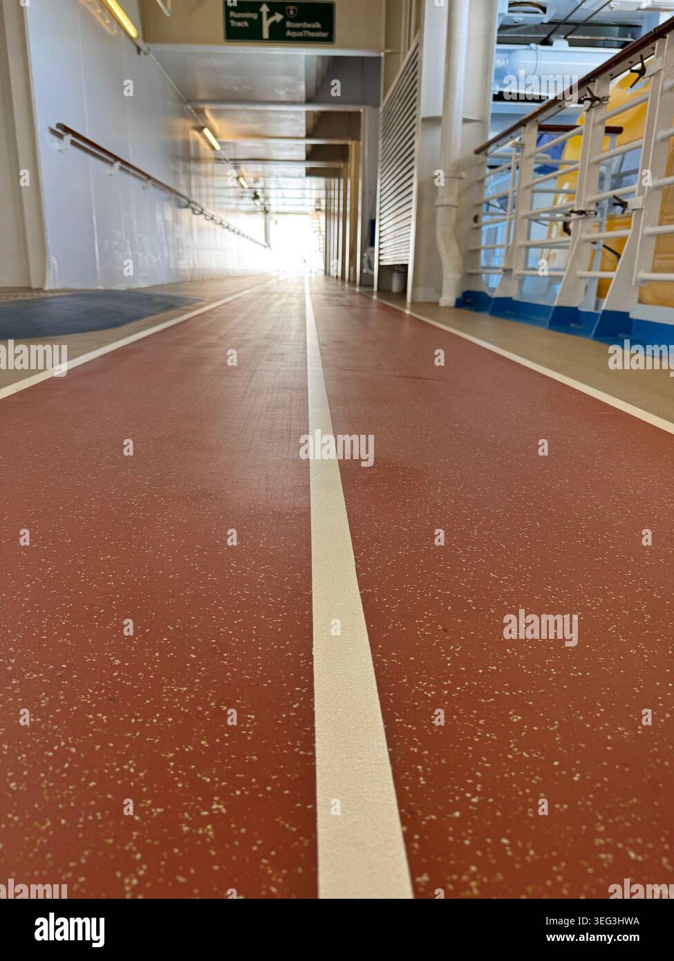 Vue en perspective à faible angle d'une piste de course et de jogging extérieure rouge avec des lignes blanches sur le pont de promenade d'un bateau de croisière. - Image de stock capturée avec un smartphone