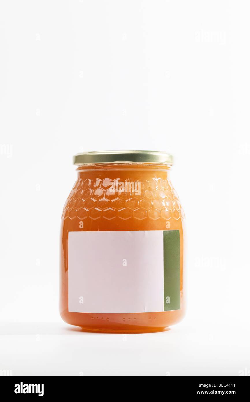 Confiture d'orange dans un pot en verre de miel de thym naturel avec surface texturée. Le couvercle en métal ferme hermétiquement le bocal. Etiquette maquette vierge, prête pour un marquage personnalisé. Banque D'Images