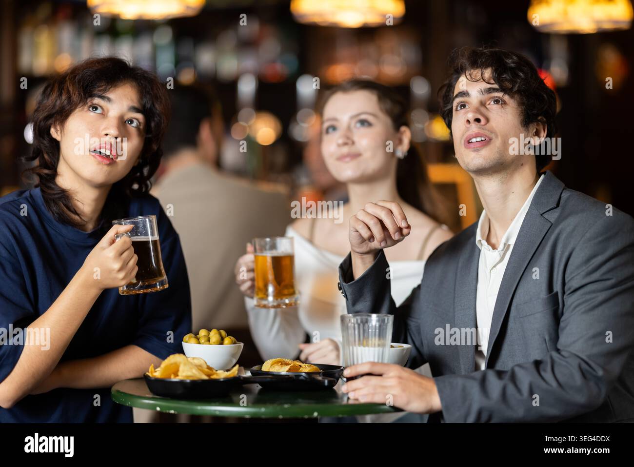 Groupe d'amis traîne au bar sportif, regardant les équipes match Banque D'Images