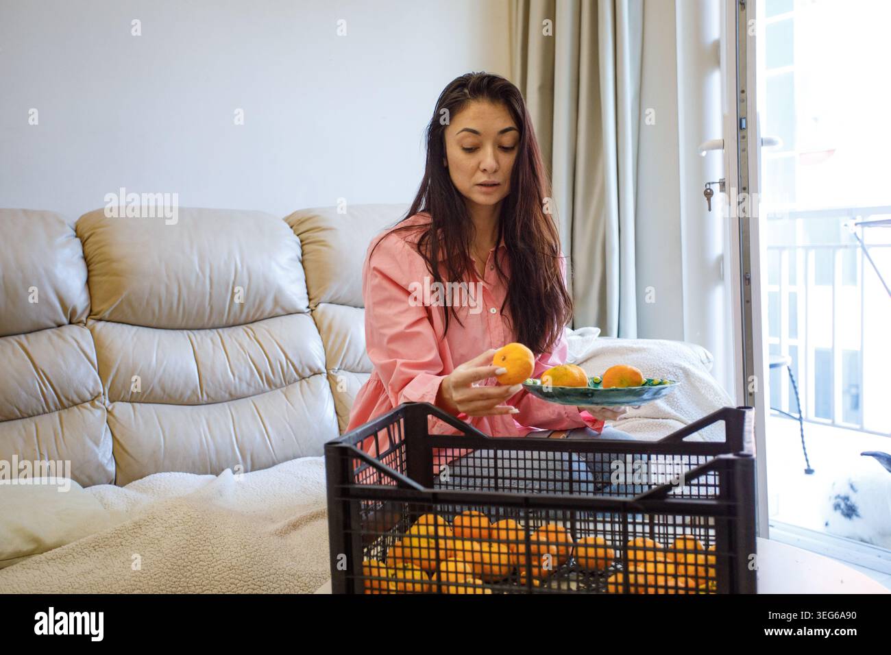 Femme heureuse mangeant des mandarines à la maison Banque D'Images