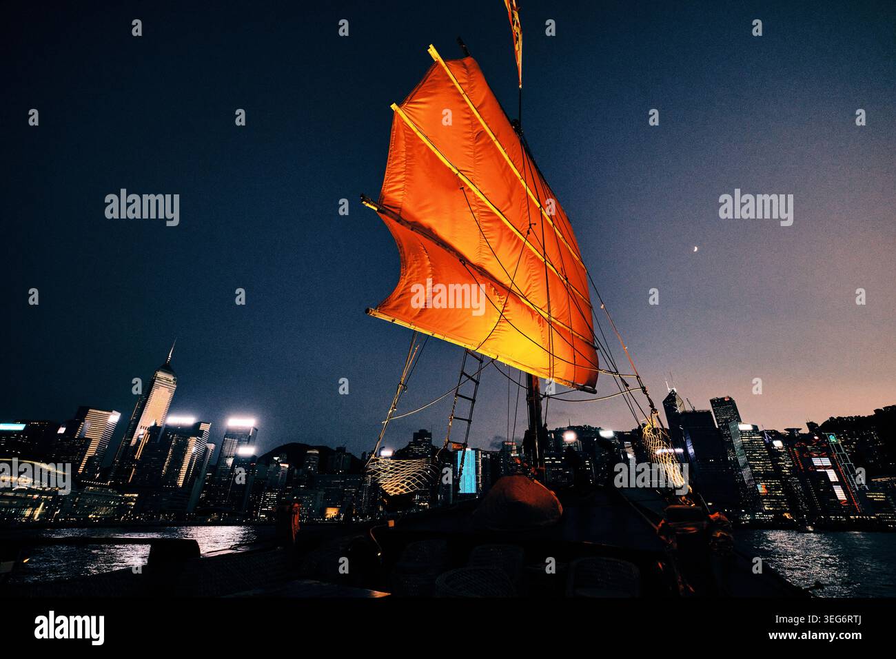 Voile rouge de la jonque Aqua Luna contre Hong Kong skyline Banque D'Images