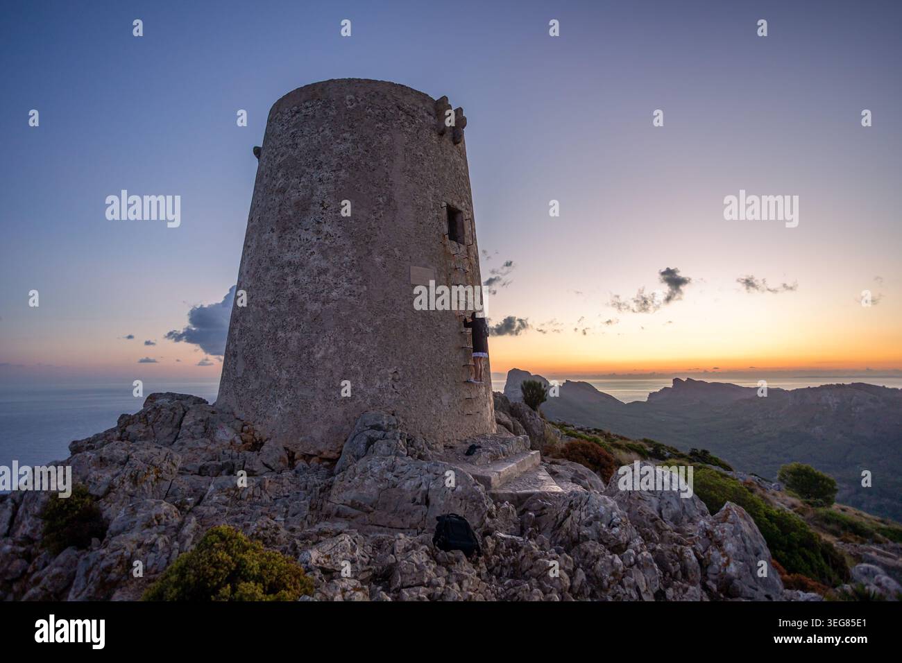 Historique Talaia d'Albercutx tour de guet sur un sommet rocheux dans le nord de Majorque pendant le coucher du soleil, avec une personne grimpant l'échelle et pittoresque côte Banque D'Images