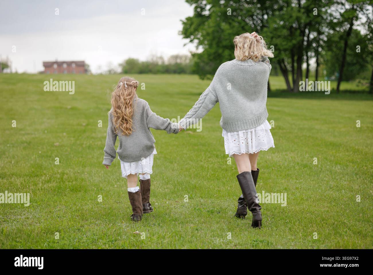 Une mère et une fille joyeuses marchent main dans la main à travers un champ verdoyant, incarnant l'amour et le bonheur, parfait pour les campagnes axées sur la famille ou Moth Banque D'Images