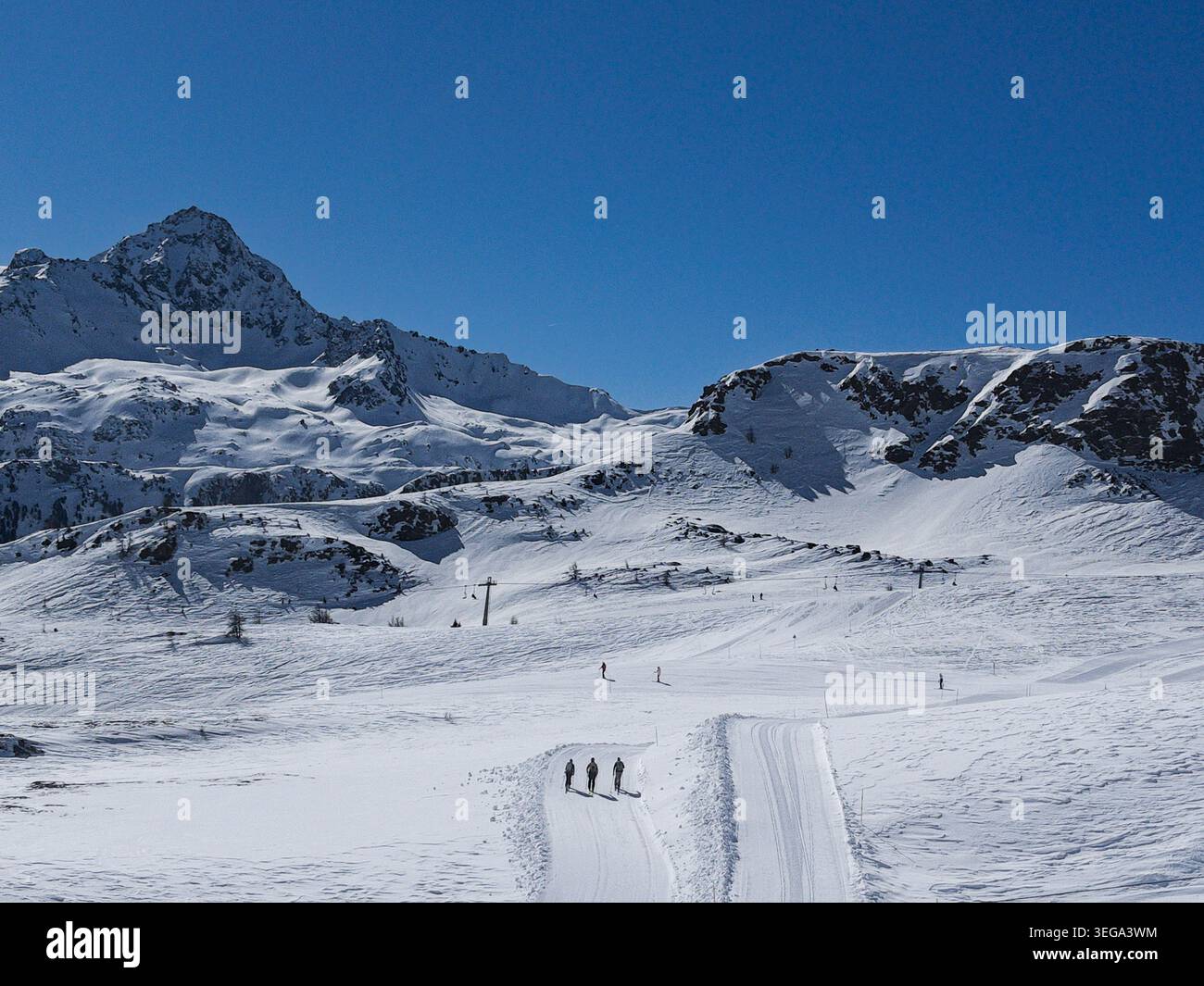 Un paysage hivernal à couper le souffle à la Thuile, en Italie, montrant des skieurs de fond suivant une piste de neige entretenue au milieu de la magnifique pe enneigée - Image de stock capturée avec un smartphone