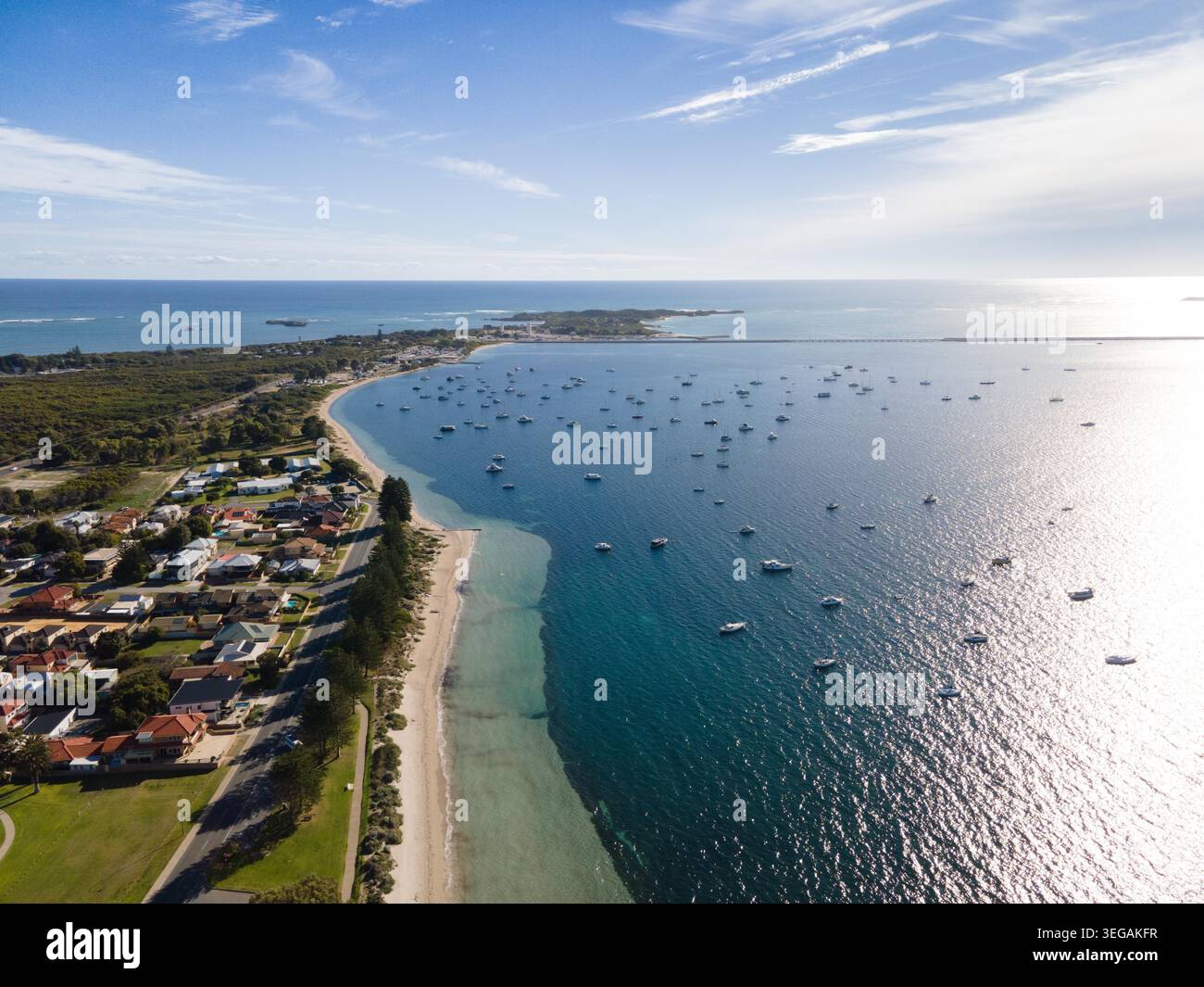 Une vue aérienne expansive mettant en valeur une ville côtière sereine nichée le long du rivage, avec une plage de sable, des vagues douces et une multitude de bateaux Banque D'Images