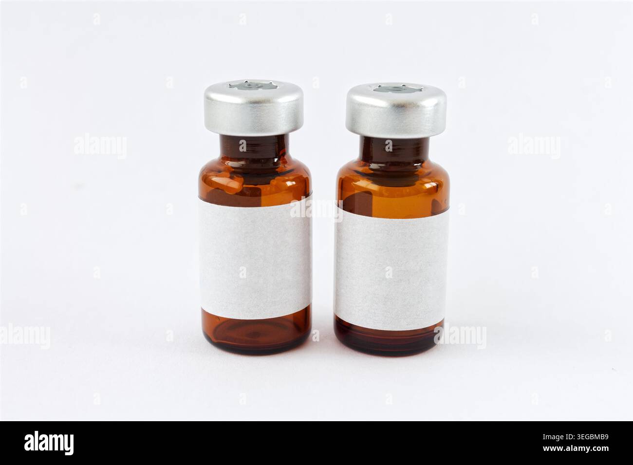 Paire de flacons médicaux en verre ambré, côte à côte sur blanc. Étiquettes vierges pour la marque pharmaceutique, les maquettes de vaccins et les soins de santé. Banque D'Images