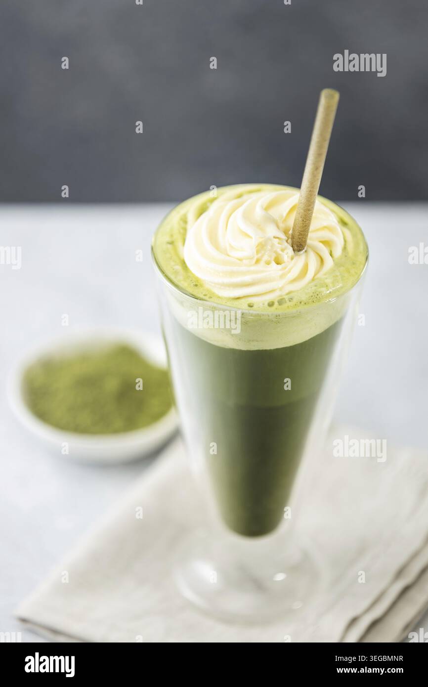 Latte matcha congelé rafraîchissant garni de crème fouettée et servi avec une paille écologique qui favorise un LIF sain et durable Banque D'Images