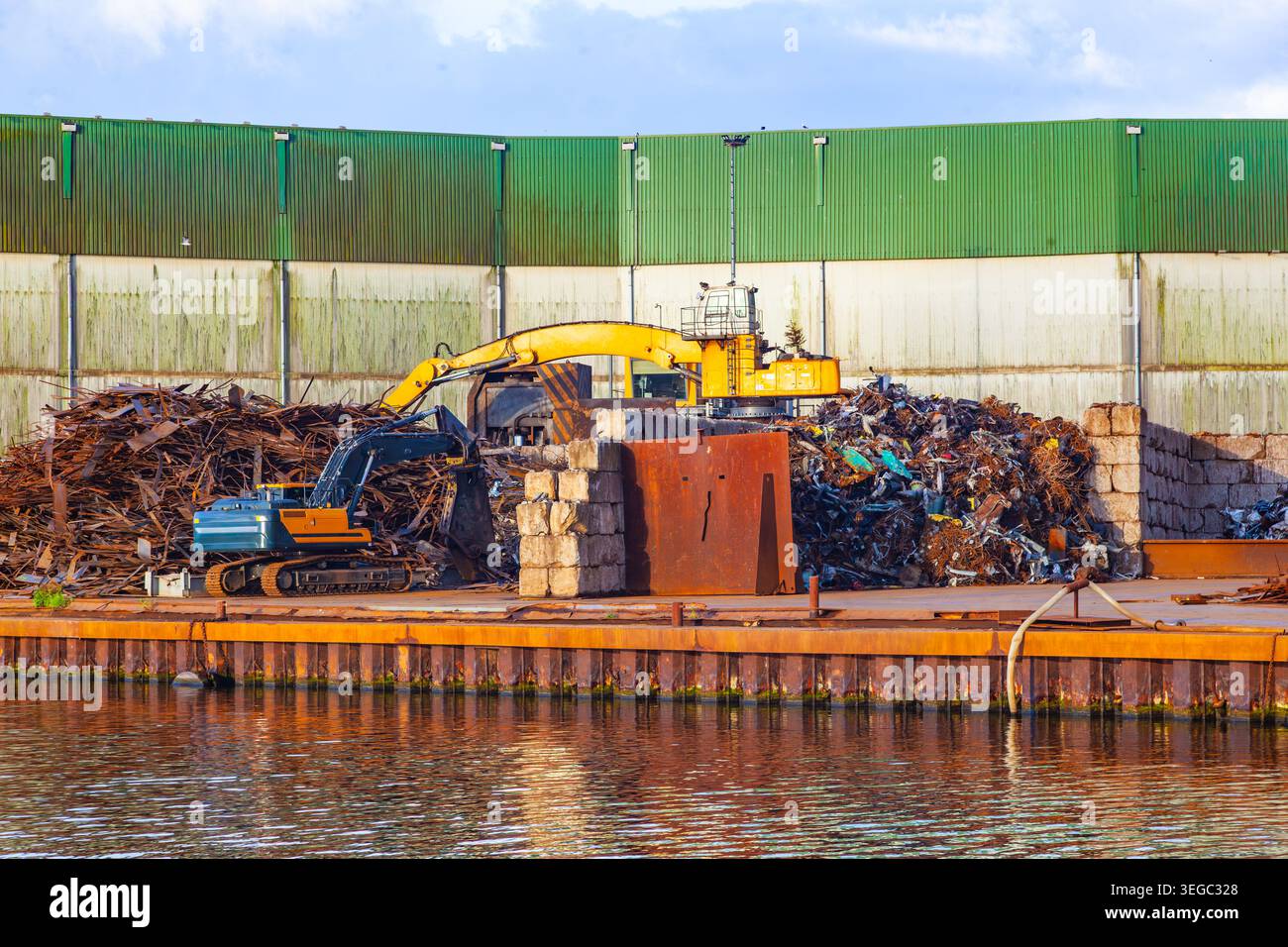 Installation de recyclage de ferraille industrielle dans un terminal portuaire avec des pelles hydrauliques et de gros tas de déchets de fer rouillé Banque D'Images