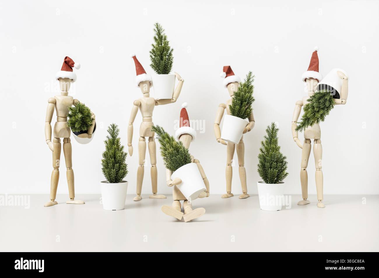 Groupe de mannequins en bois dans les chapeaux du Père Noël tenant des arbres de Noël. Arrière-plan de Noël Banque D'Images