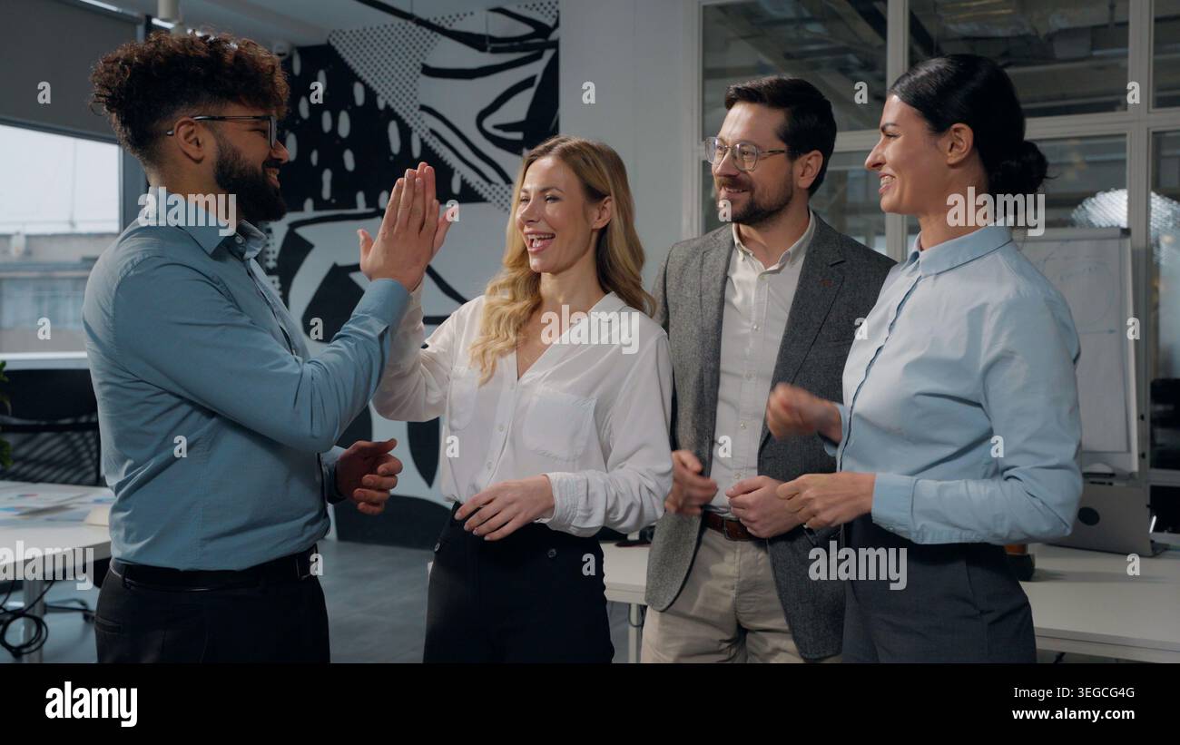 Diversité quatre collègues gestionnaires de bureau d'affaires multiethniques discutant du travail donnant haut cinq trouver une bonne solution triomphent les femmes d'affaires caucasiennes Banque D'Images