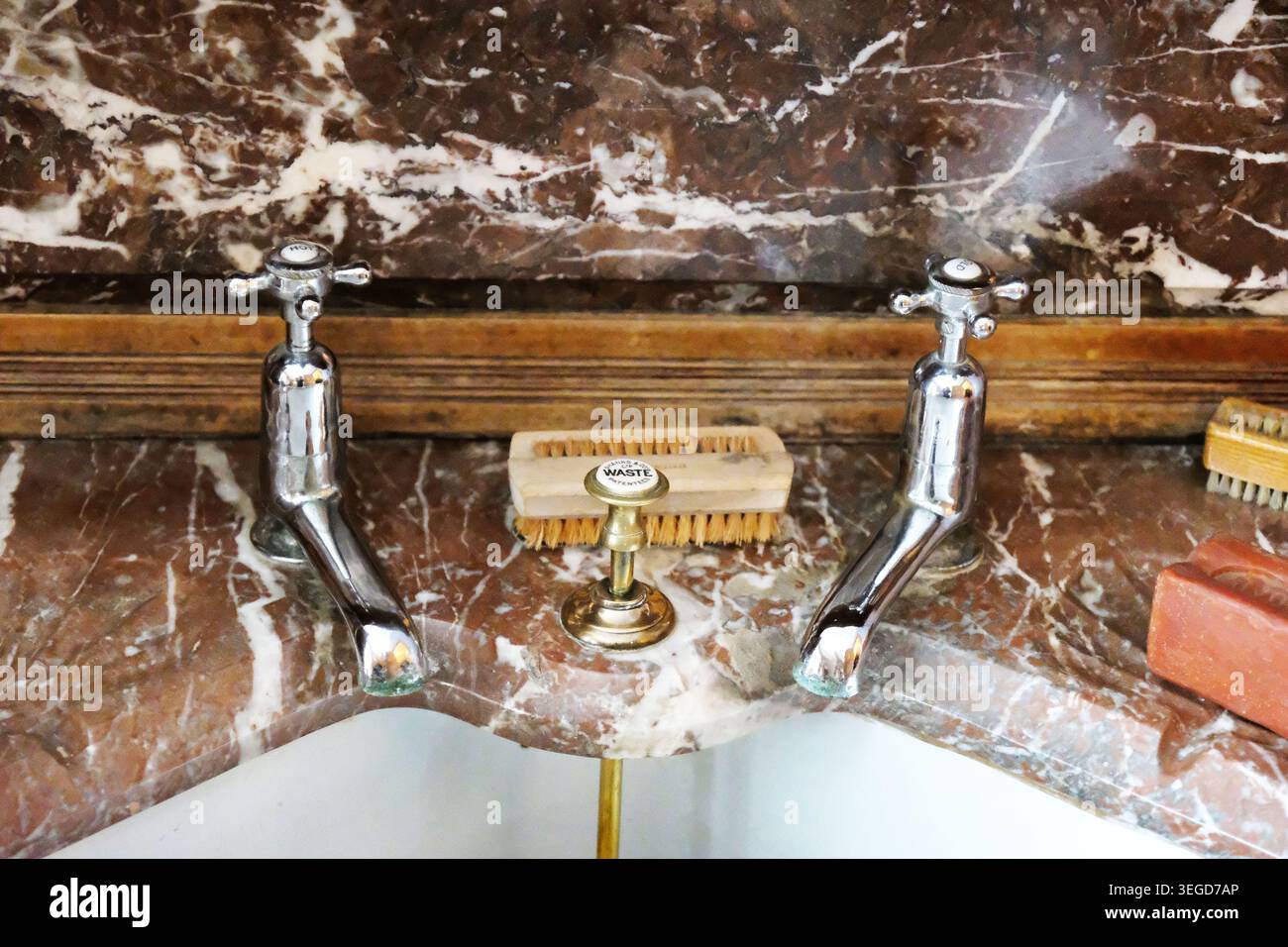 Gros plan de robinets d'eau chromés vintage séparés avec poignées transversales installées sur un lavabo en marbre veiné brun splashblack. Banque D'Images