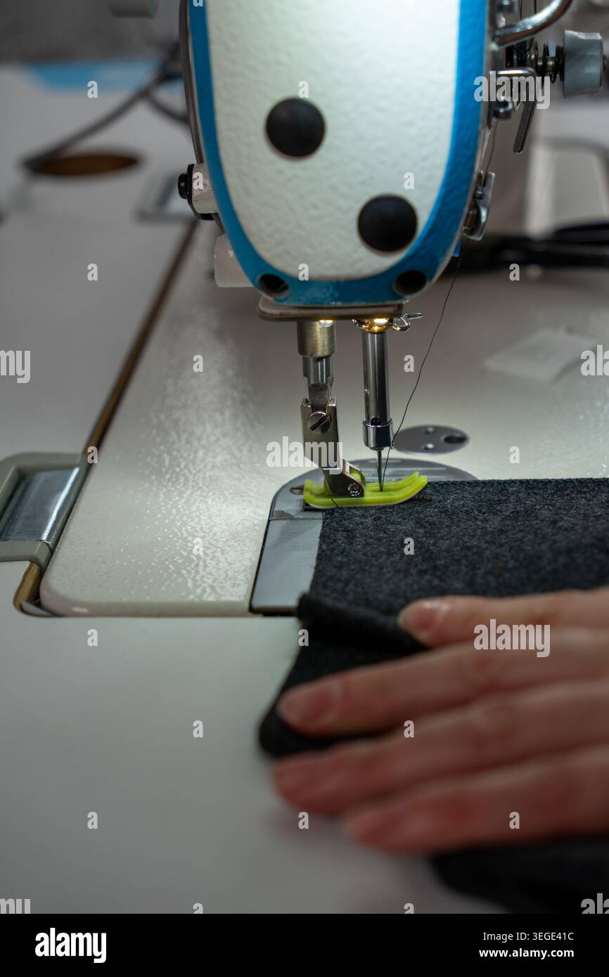 Gros plan vertical du processus de couture avec tissu, fils et machine à coudre pendant la production de vêtements. Travail textile détaillé avec des points, couture Banque D'Images