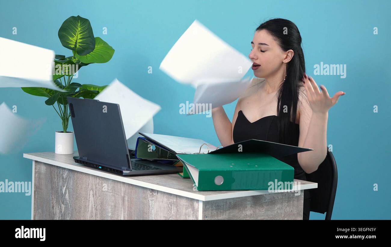 Femme d'affaires en colère travaillant à la table d'ordinateur portable jetant des papiers Banque D'Images
