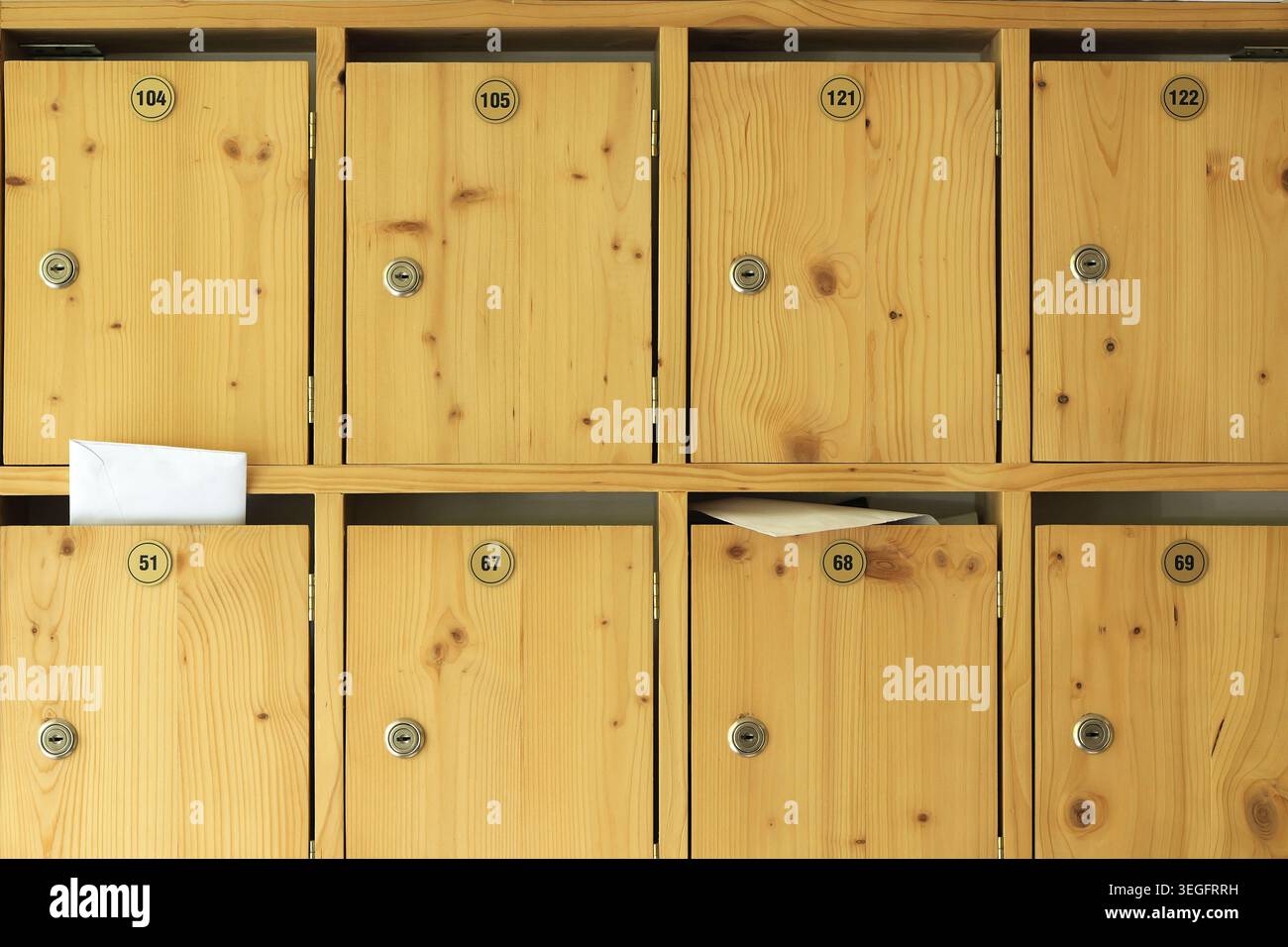Rangée de boîtes aux lettres en bois numérotées avec des portes et des fentes verrouillées, certaines contenant des lettres et des enveloppes, détail rapproché du système de courrier résidentiel pour secur Banque D'Images