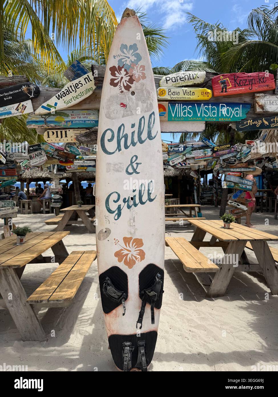 Une planche de surf décorative avec le texte « Chill & Grill » debout dans un bar de plage tropical extérieur à Curaçao. - Image de stock capturée avec un smartphone