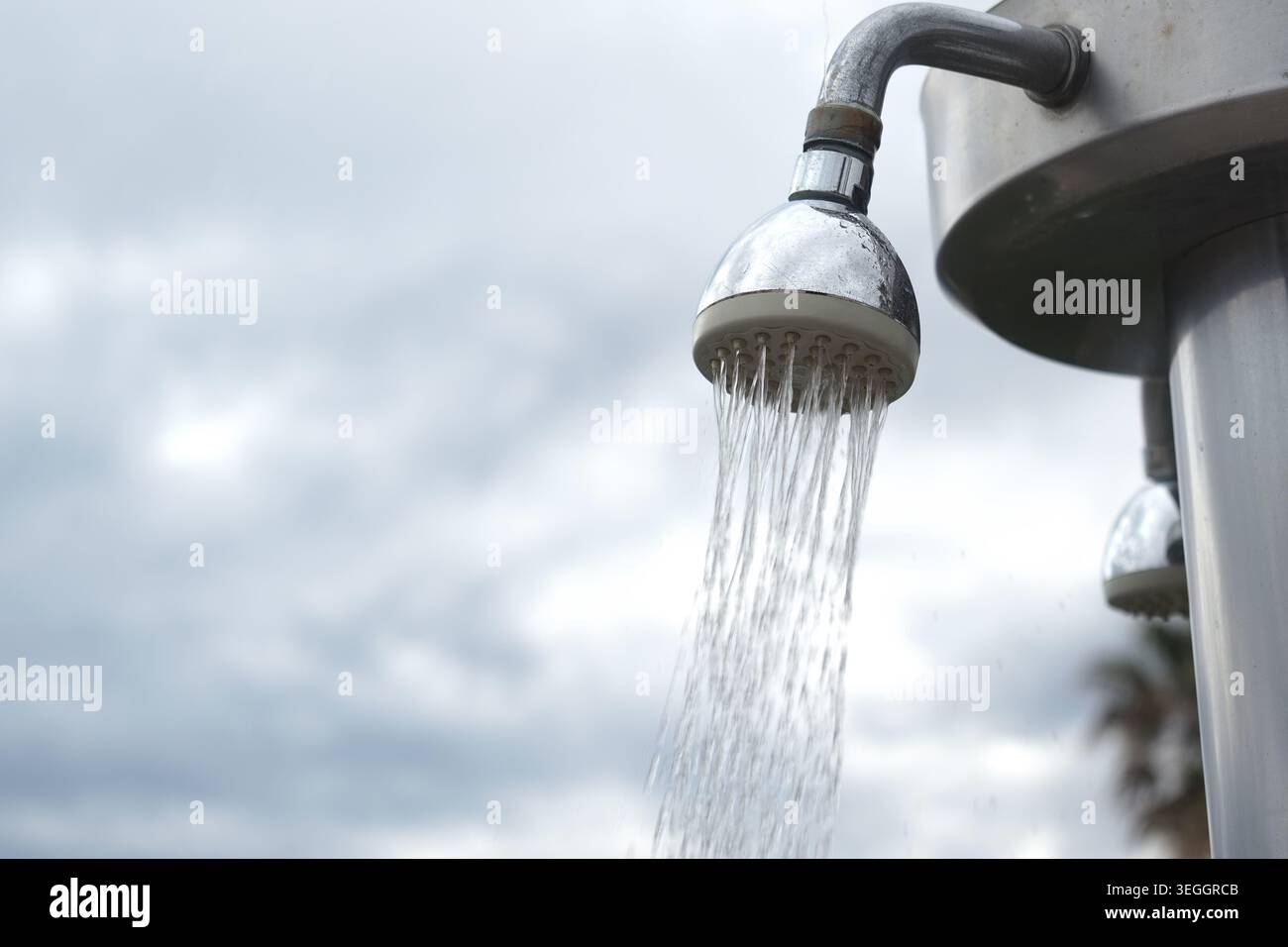 L'eau coule d'une pomme de douche dans un cadre extérieur Banque D'Images