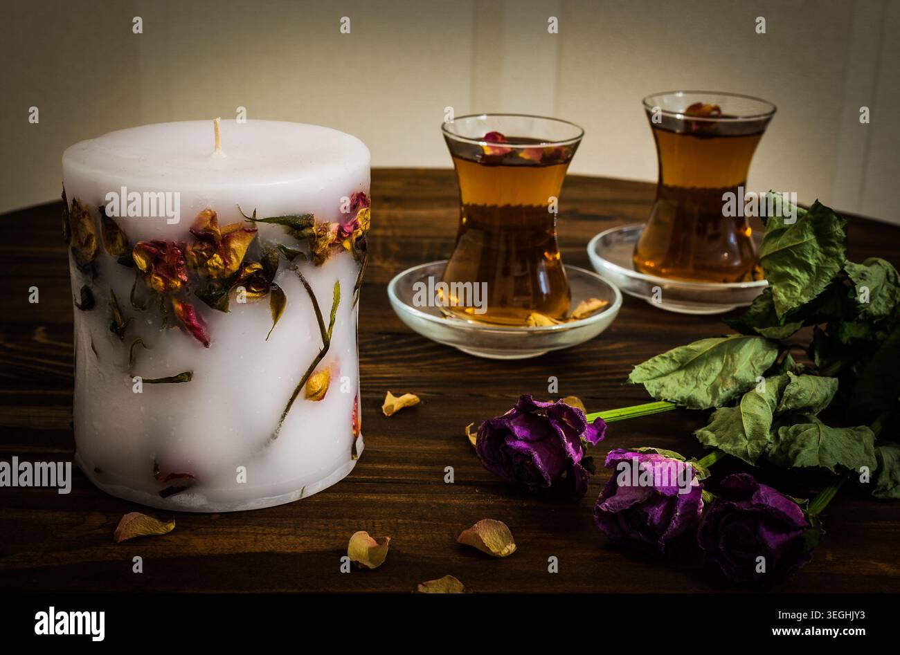 Ambiance chaleureuse d'une partie de thé orientale avec deux verres traditionnels armudu remplis de tisane chaude sur une table en bois sombre avec une bougie faite à la main Banque D'Images