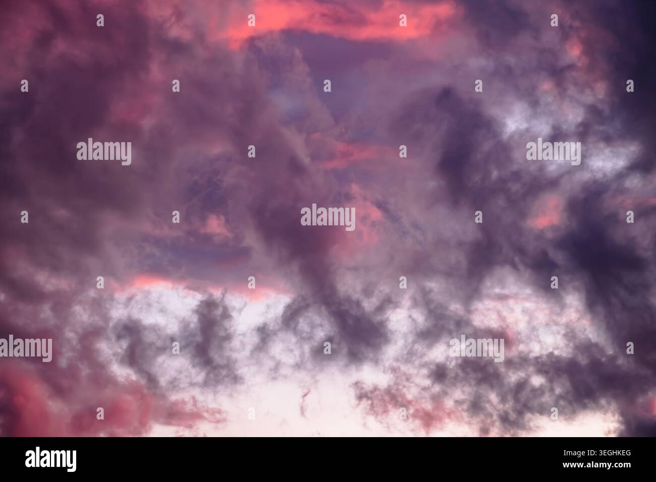 Ciel nuageux spectaculaire au crépuscule, avec des violets riches et une lumière rose et orange rougeâtre. Évaporation après tempête. Ciel coloré Banque D'Images