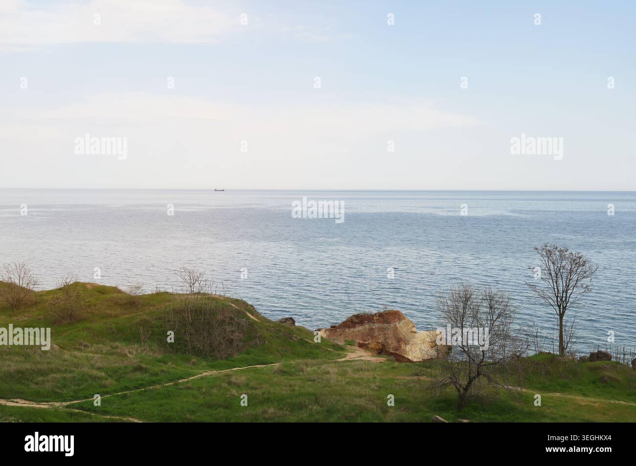 Large panorama sur la mer bleue calme avec des collines verdoyantes et des rochers au premier plan. Concept de beauté de la nature côtière, découverte de voyage de printemps, et serein Banque D'Images