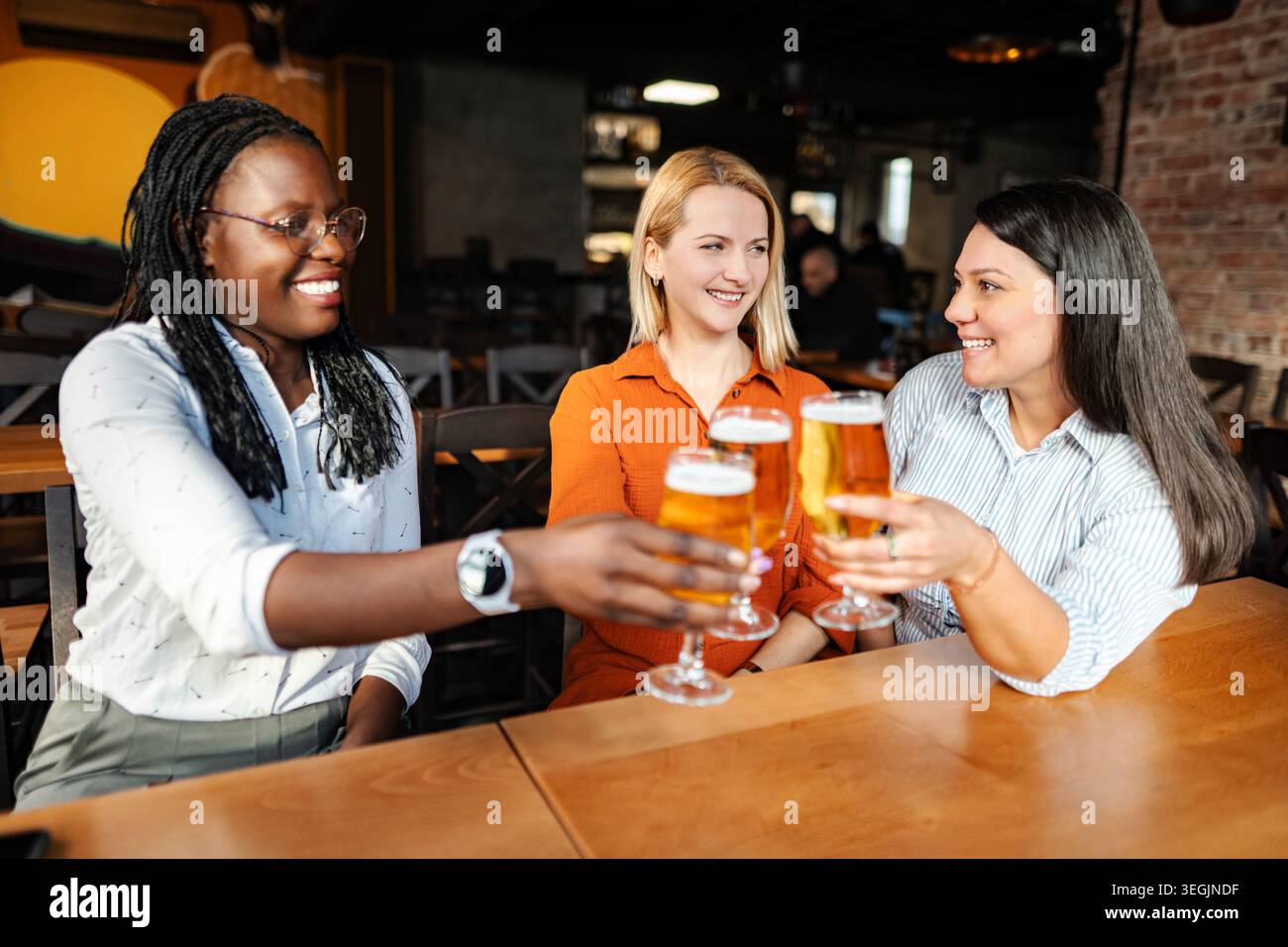 Diverses femmes amies grillant la bière dans un bar Banque D'Images