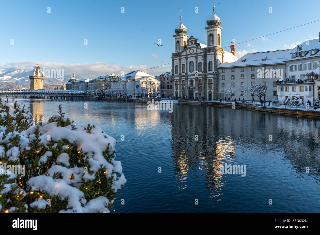 L'église jésuite baroque se dresse majestueuse au bord de la rivière, encadrée par la neige et les lumières festives de l'hiver Banque D'Images