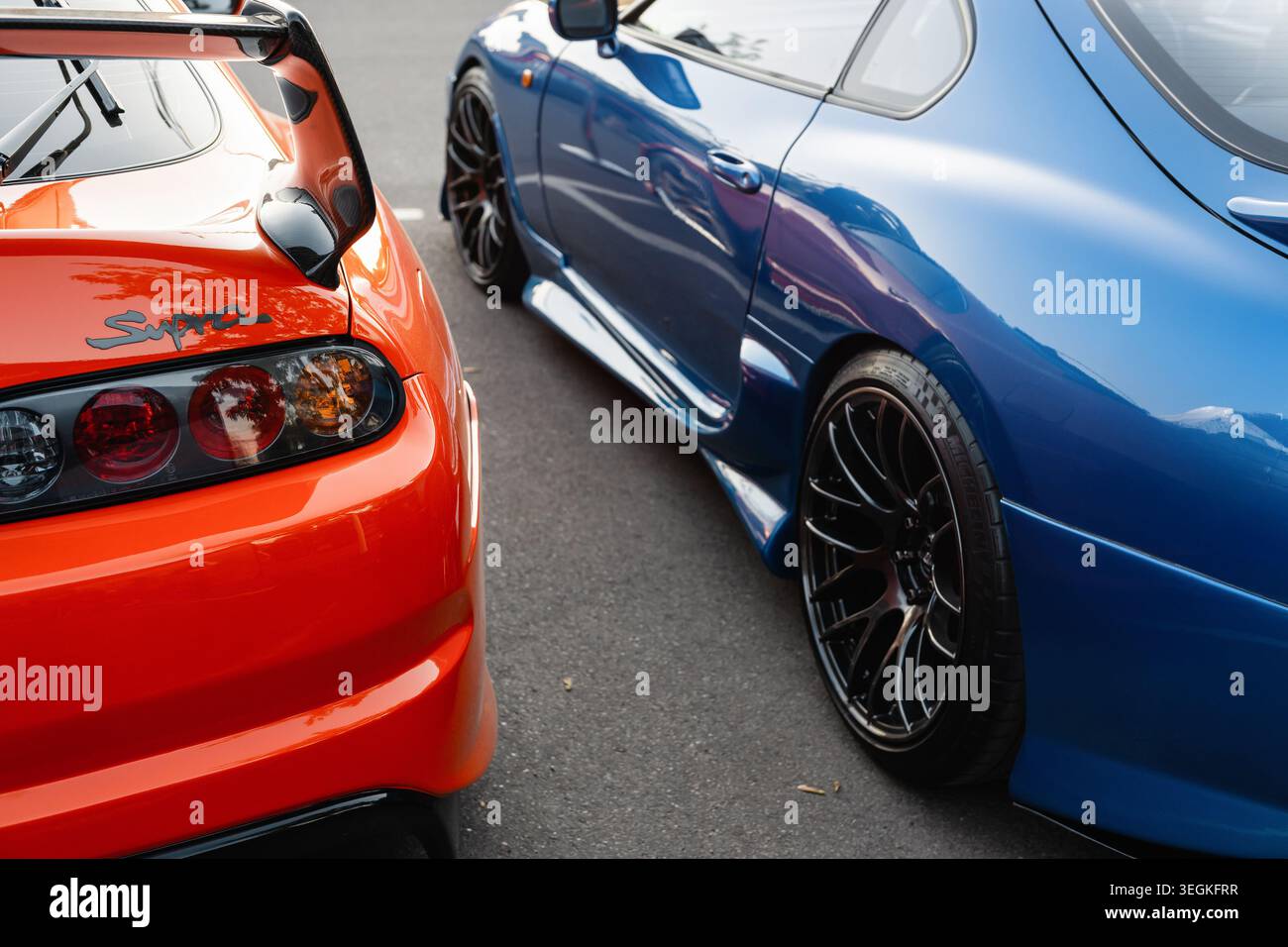 Paire de voitures de sport Toyota Supra A80 côte à côte - orange et bleu. Vue arrière et latérale rapprochée de deux voitures de sport japonaises Totota Supra mk4 Banque D'Images